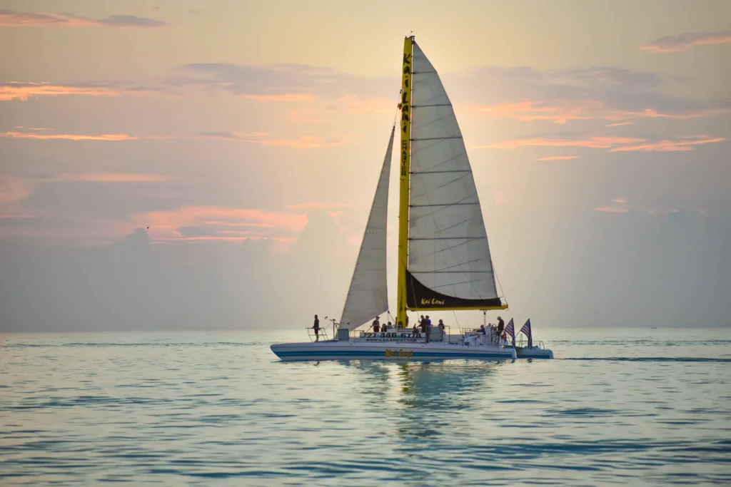 Sailboat carrying passengers on calm water at sunset in Naples, Florida.