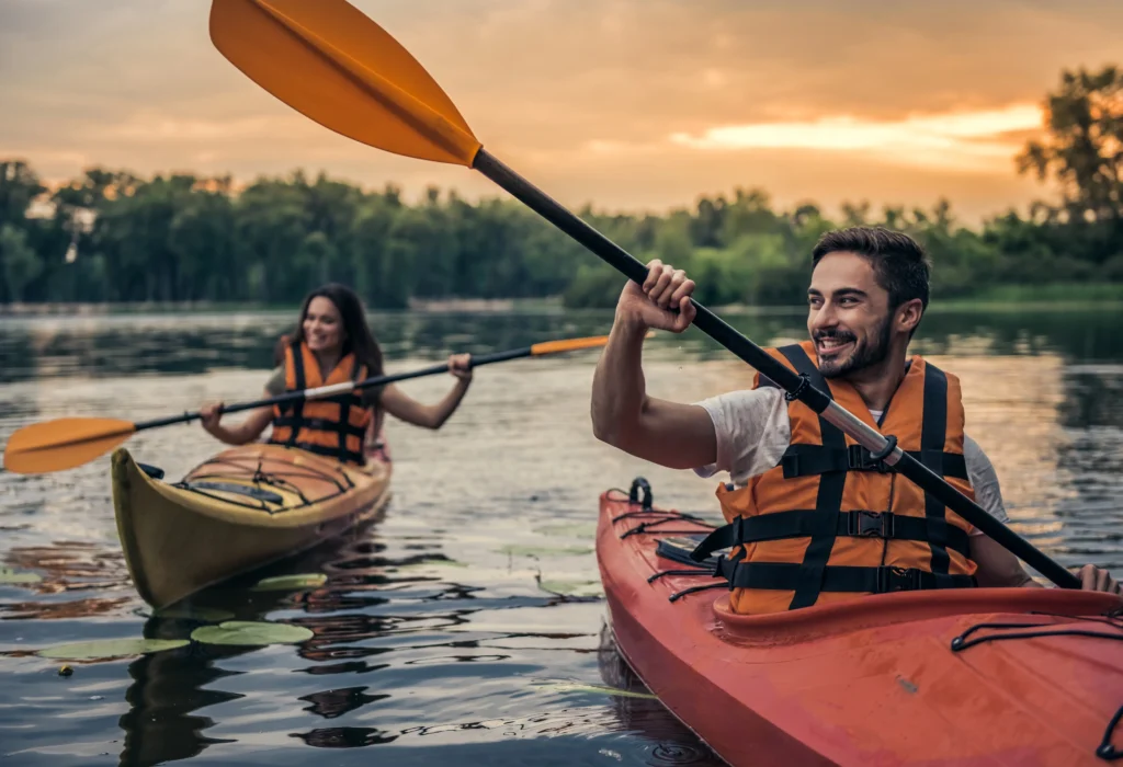 Couple kayaking on a lake at sunset.
